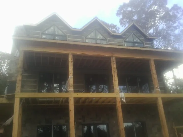 Dormers and porch framing on a large log home under construction — Roof Coating work by our crew in Paynesville