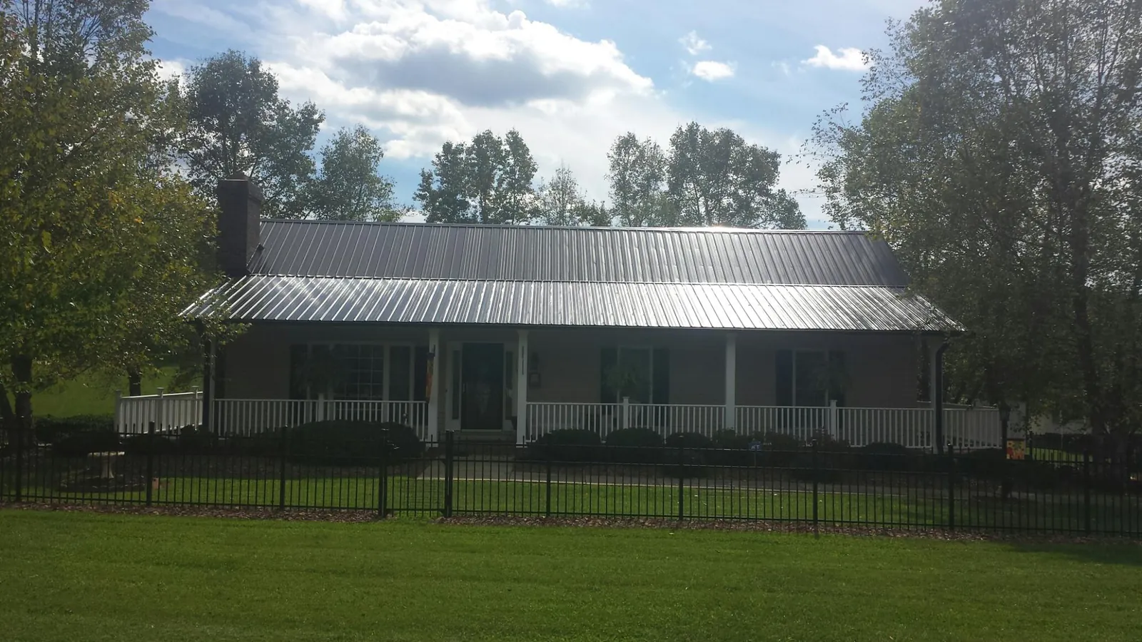 Gray metal roof on a brick ranch with a full width front porch — Gutter Guard Installation work by our crew in Paynesville
