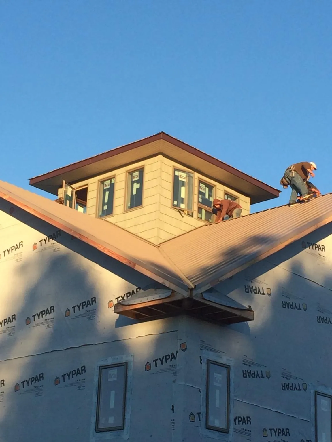 Roofers working around a rooftop cupola on a new metal roof at sunset — Roof Waterproofing in Paynesville by Roofing Brothers